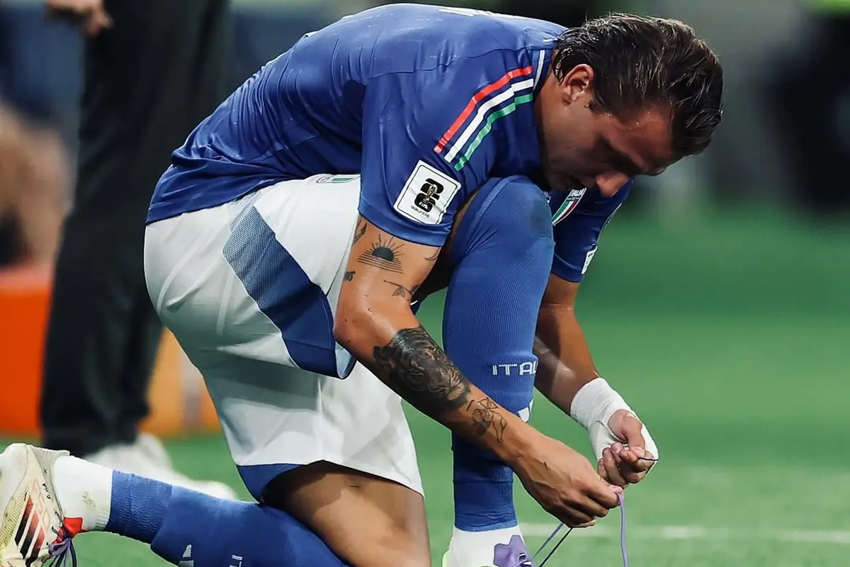 Retegui si allaccia le scarpe durante una partita della nazionale